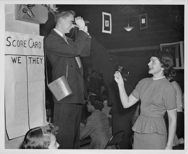 Archival photograph of 1950s Loyola students keeping score during a card party.