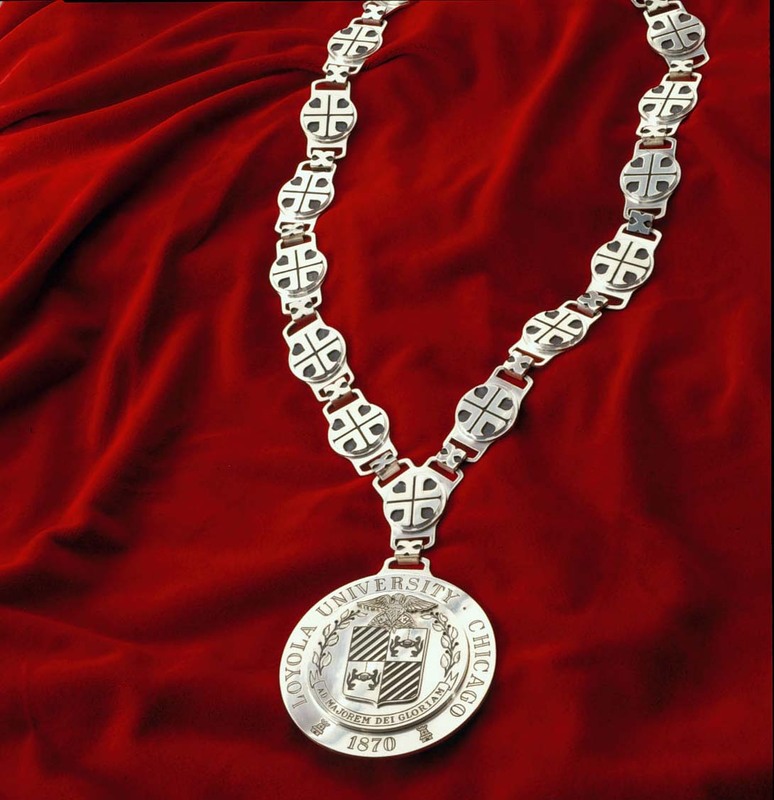A silver medallion with the Loyola University Chicago seal on the end of a silver link chain.