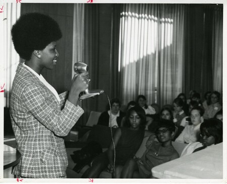 Student stands and speaks in front of a group of students (1968).