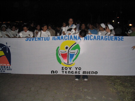 A group of people holding a banner and marching to commemorate the Salvadoran martyrs.
