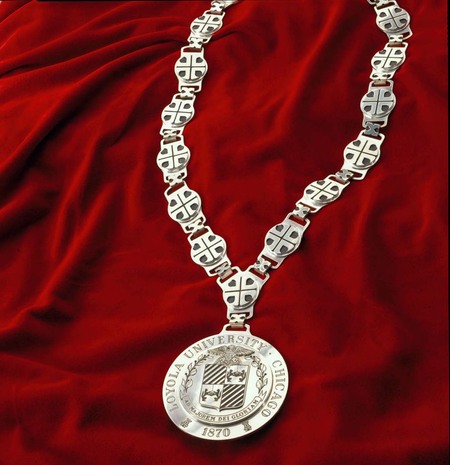 A silver medallion with the Loyola University Chicago seal on the end of a silver link chain.